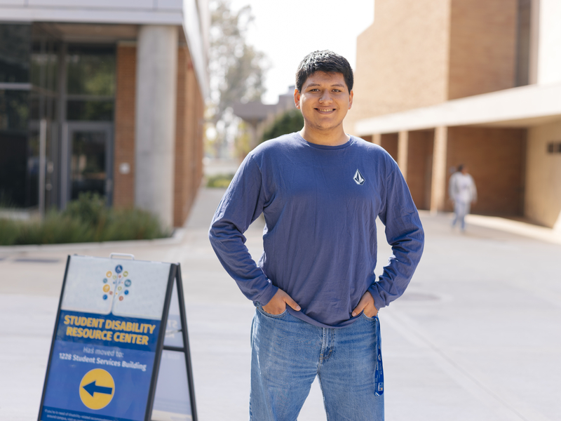 A man standing next to the Student Disability Resource Center sign at UC Riverside